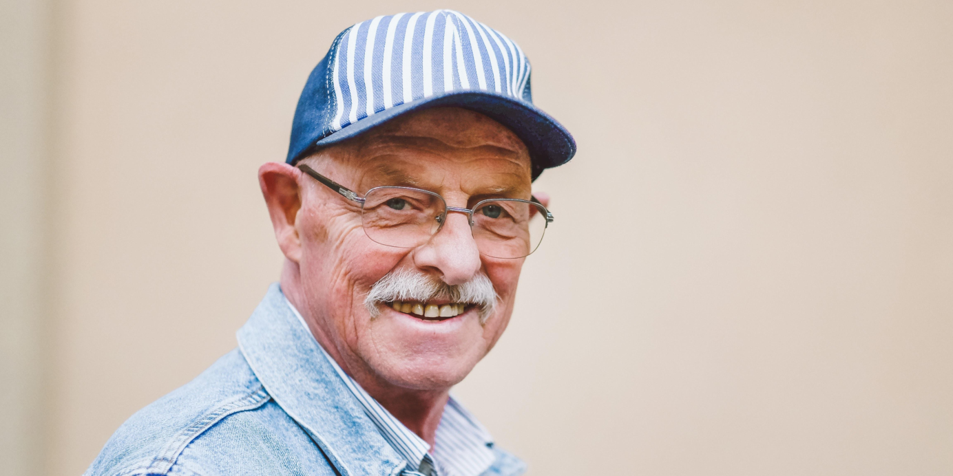 oude man met grijs haar en een snor met een pet