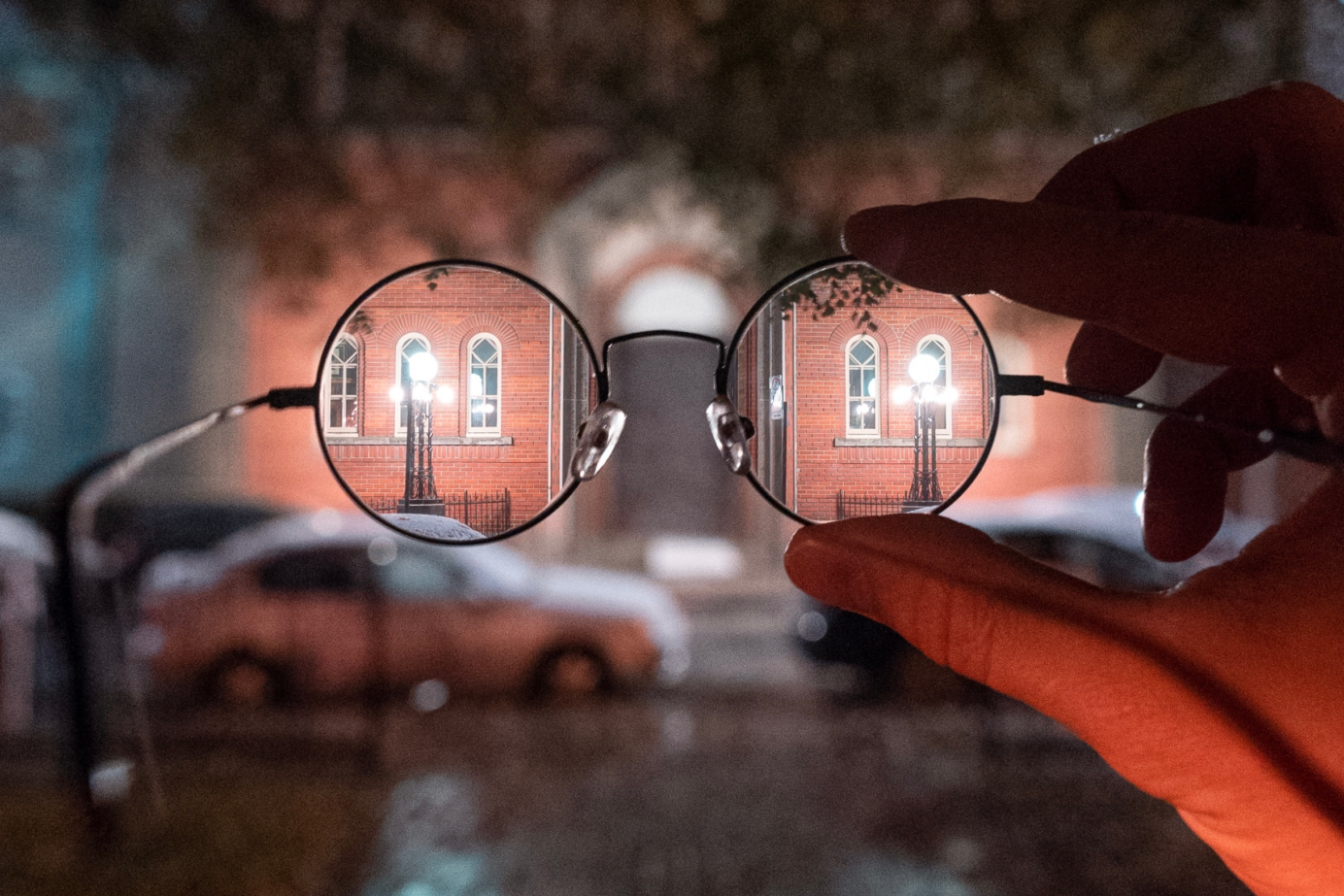 Kijken door een bril naar een straat met vertekend beeld