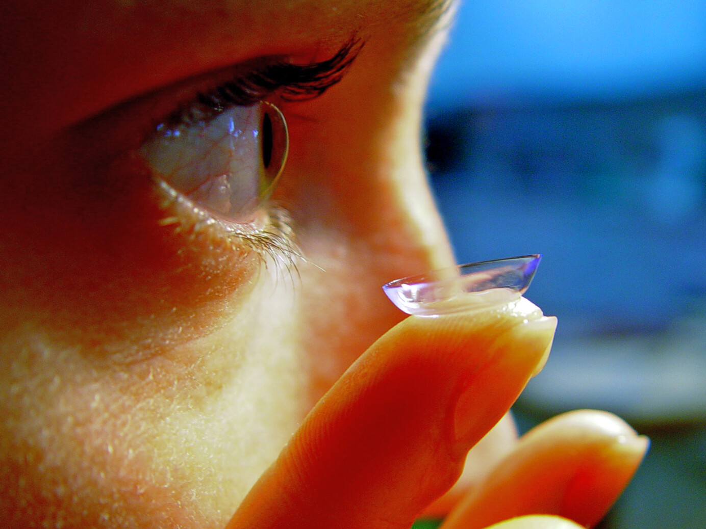 Gezicht en contactlens op vinger