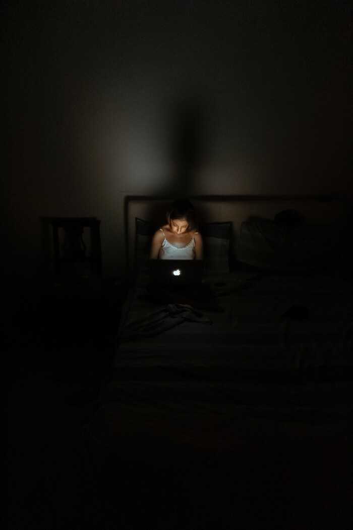 vrouw kijkt in donker op laptop