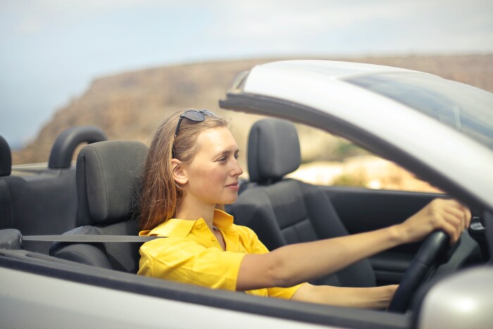 Jonge vrouw aan het autorijden in cabrio