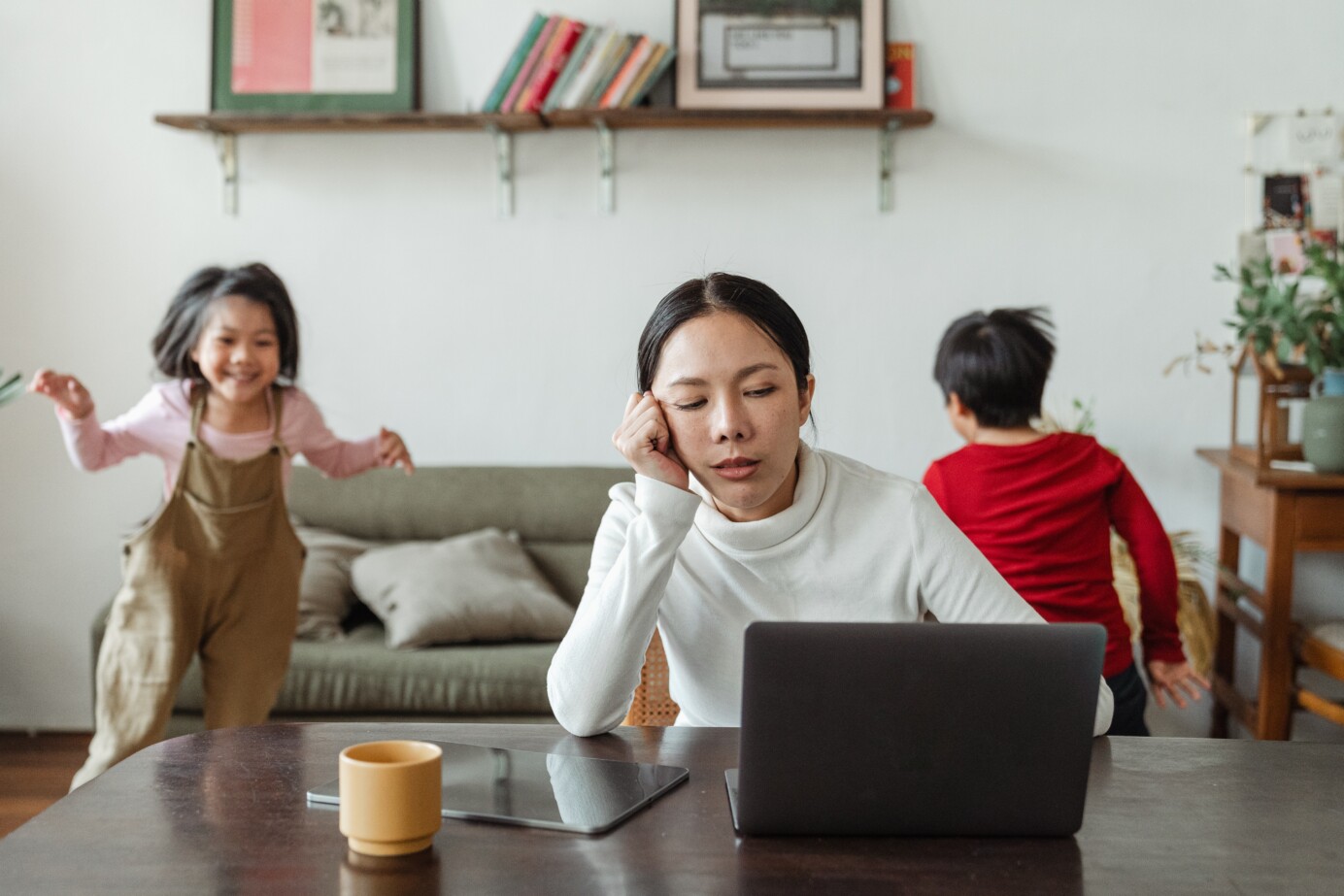 Gestreste vrouw met kinderen achter laptop