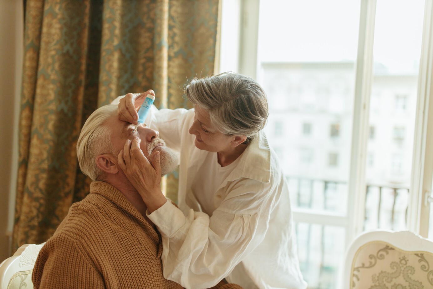 Vrouw dient oogdruppels toe bij oudere man
