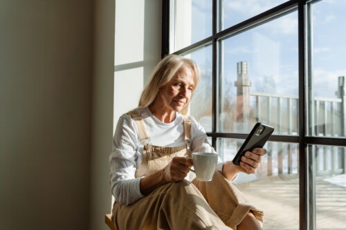 Oudere vrouw drinkt koffie in haar raam