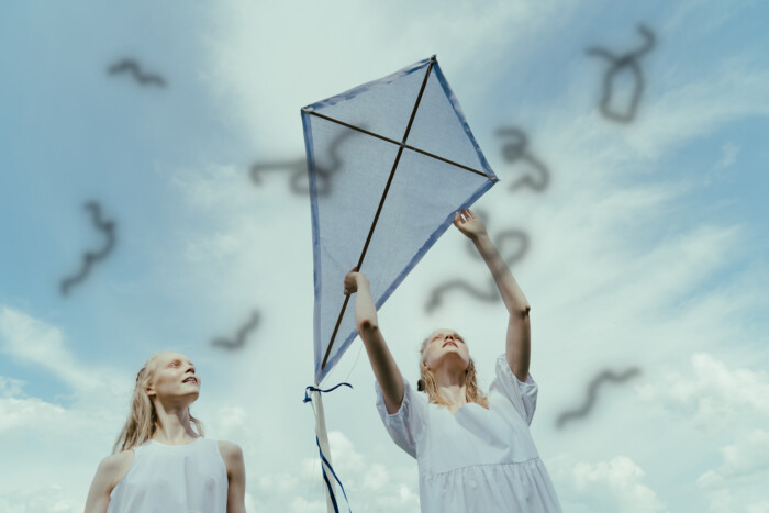 Mouches volantes (zwarte, zwevende puntjes) in het zicht op twee jonge vrouwen met een vlieger