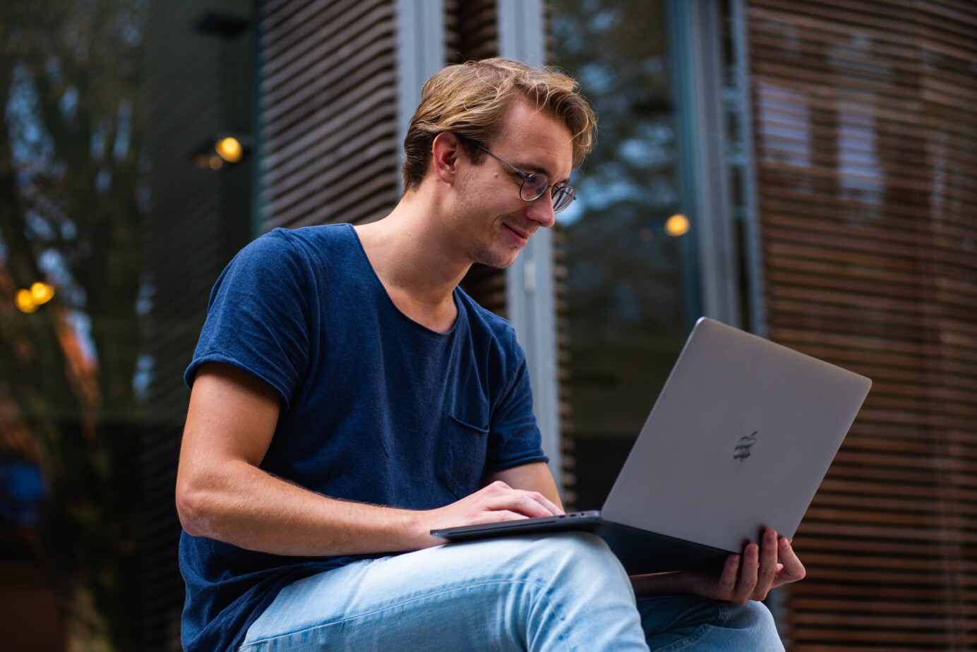 Jonge man met computerbril op werkt buiten op zijn laptop