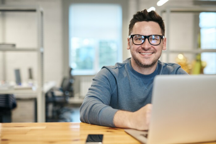 Man met computerbril op werkt op een laptop