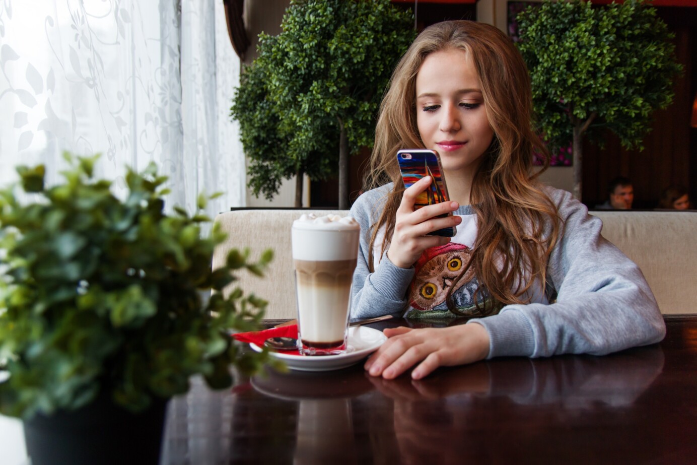 Tienermeisje kijkt naar haar telefoon in een café