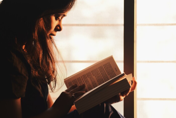 Vrouw leest een boek bij een raam